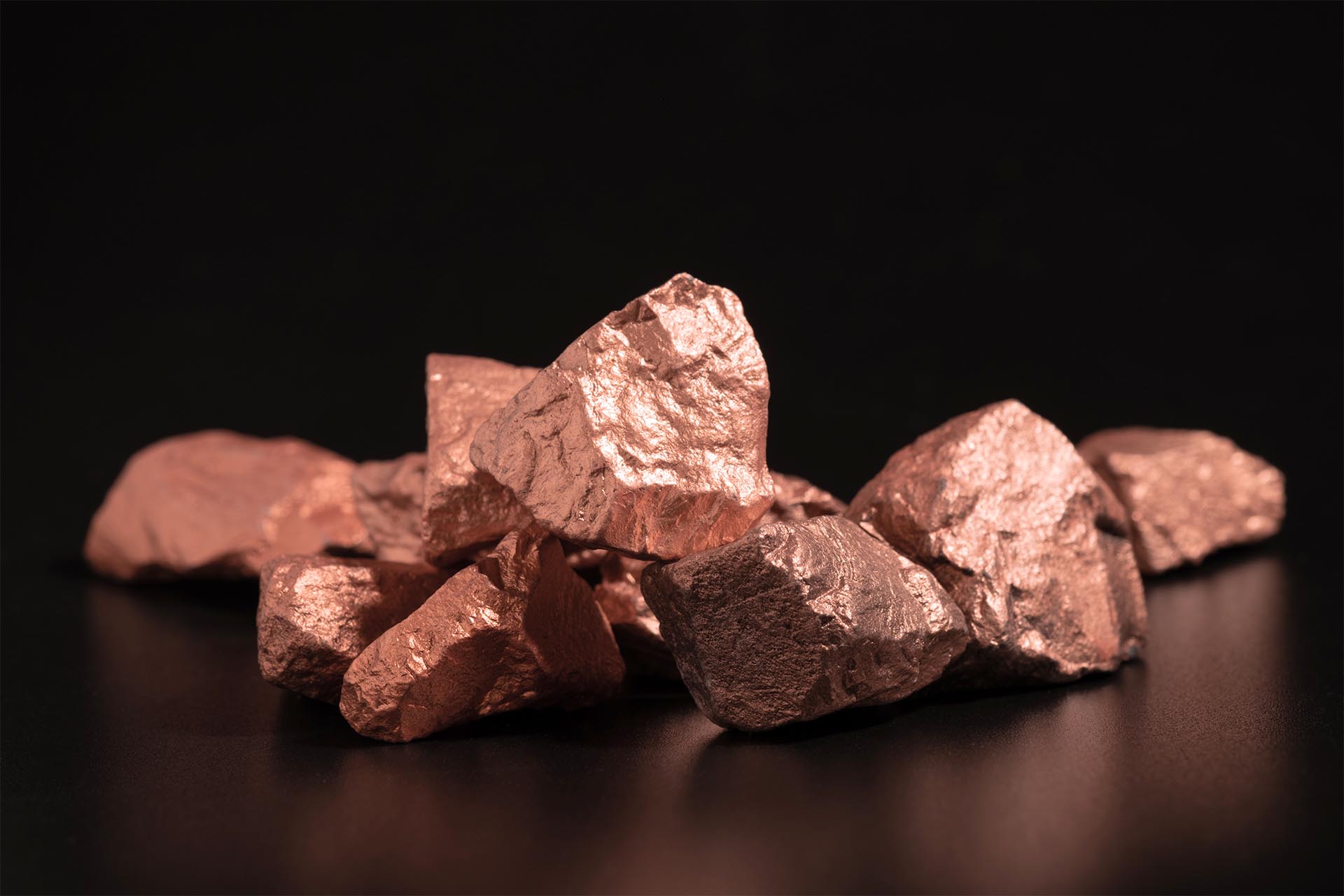 Ingots of pure copper or pink gold on a black background.